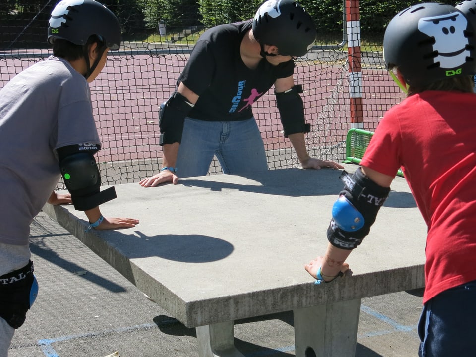 Jugendliche auf Skateboards rund um einen Pingpong-Tisch.