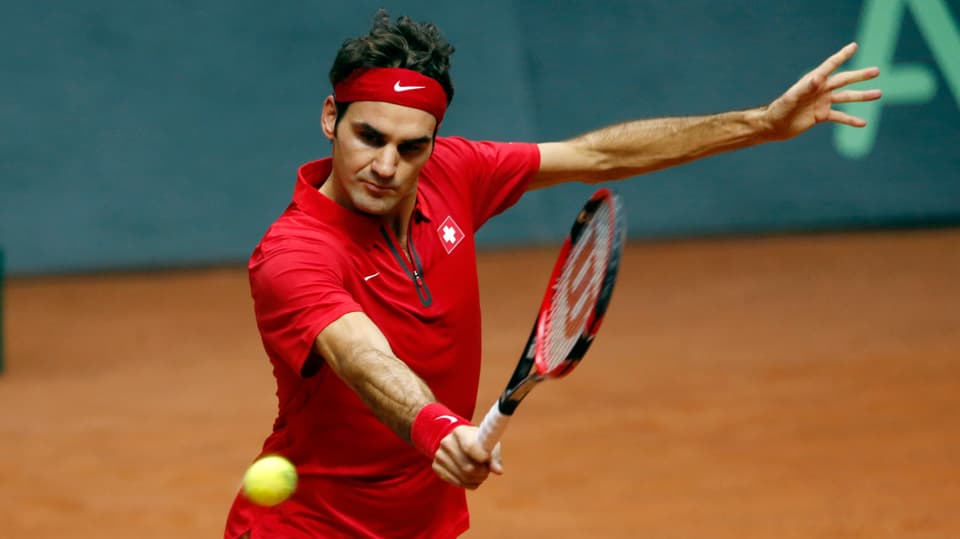 Roger Federer fokussiert einen herannahenden Ball und schlägt eine Rückhand.