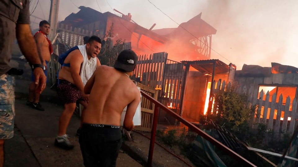 Männer an einem brennenden Gebäude.