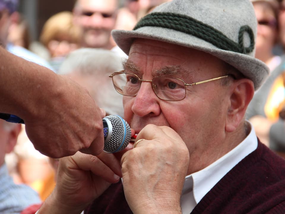 Besucher spielt auf einer Mini-Mundharmonika.