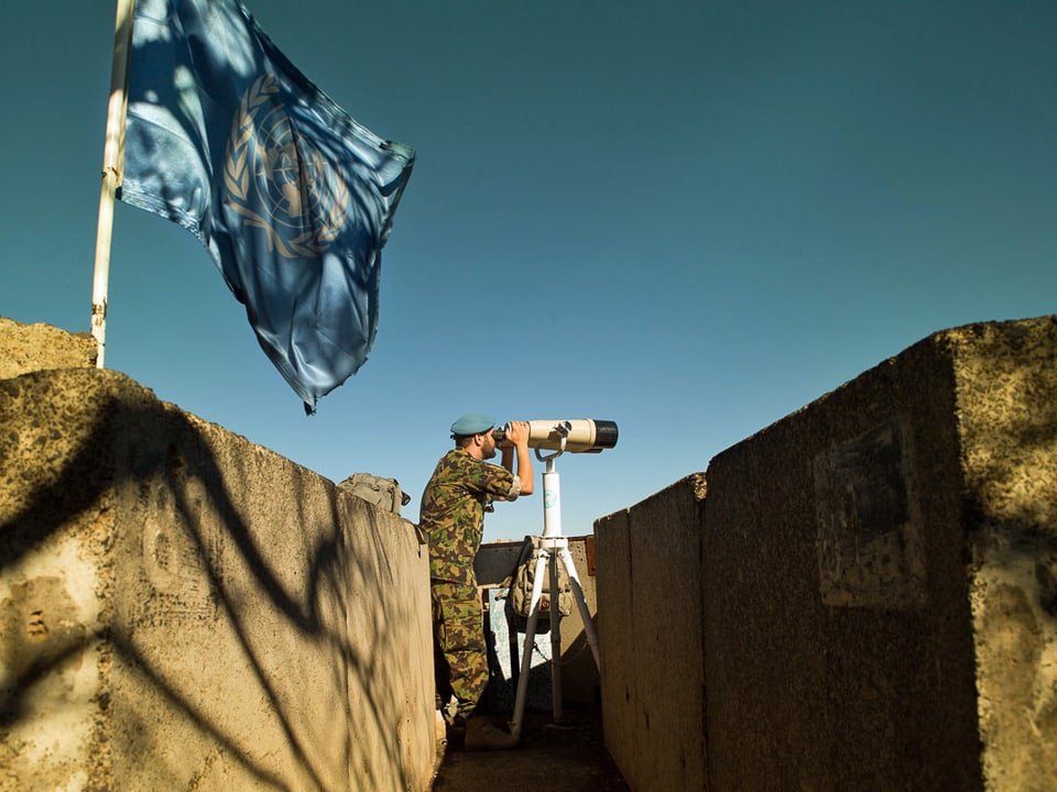 Ein Militärbeobachter späht an einem Beobachtungsposten durch ein fernrohr über die Golan-Höhen. (Michael Calabrò)