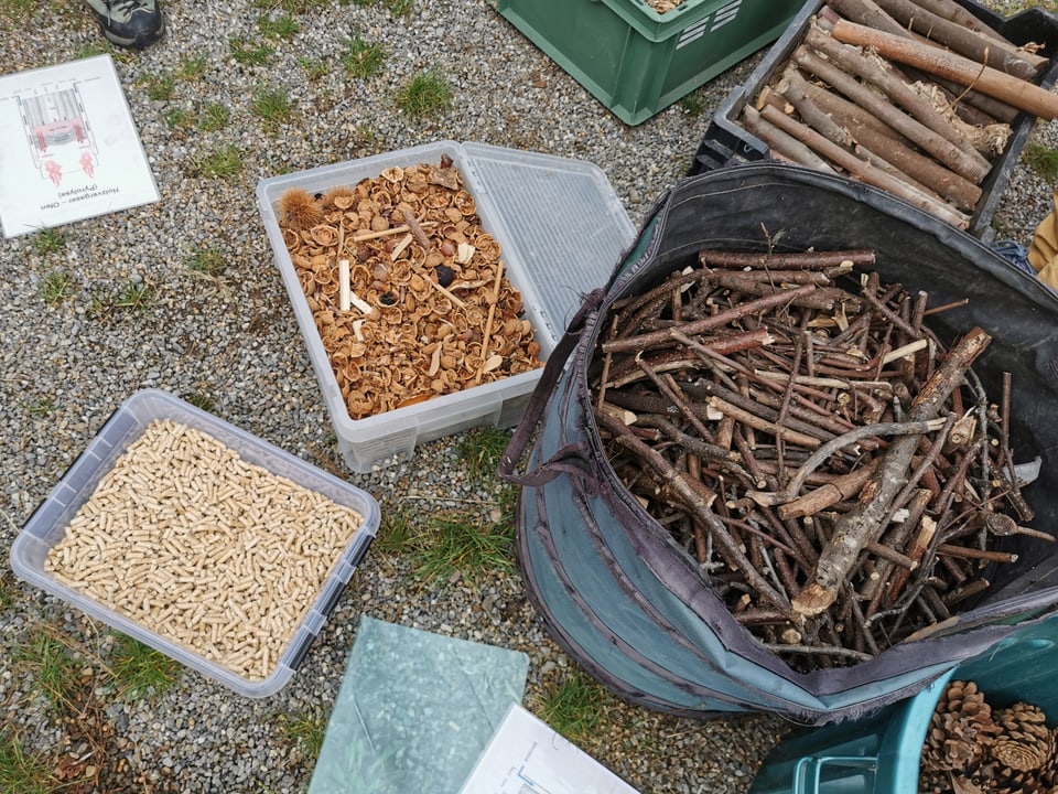 Behälter gefüllt mit getrocknetem Pflanzenmaterial stehen auf dem Boden.