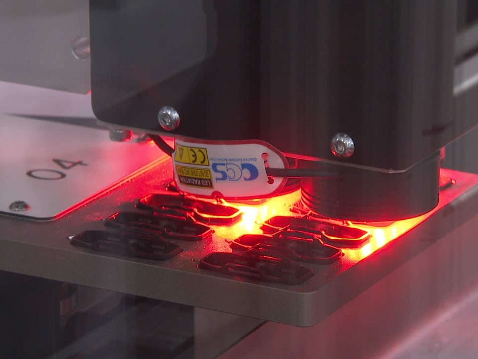 Roboter Nahaufnahme: Roter Laser kontrolliert die Qualität der Analyseplatinen.