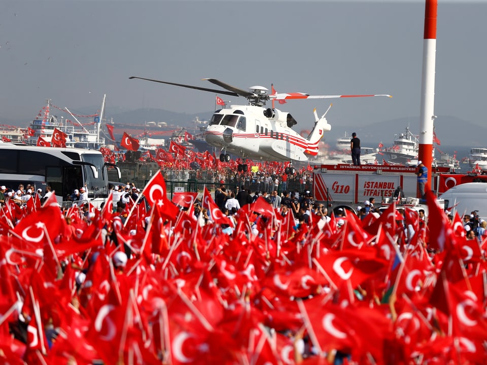 Ein Helikopter landet Nahe von tausenden Menschen, die Türkei-Flaggen halten
