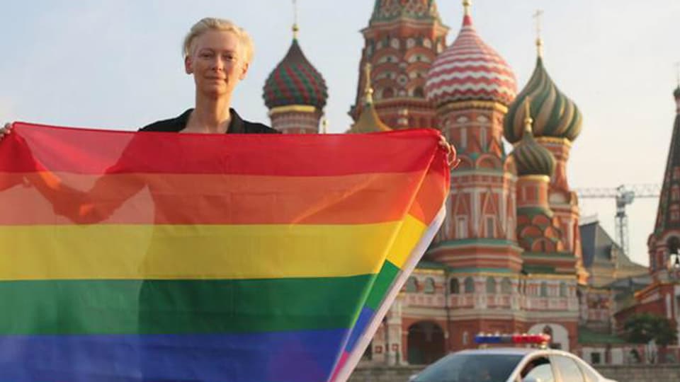 Tilda Swinton mit der Regenbogen-Flagge vor dem Moskauer Kreml stehend
