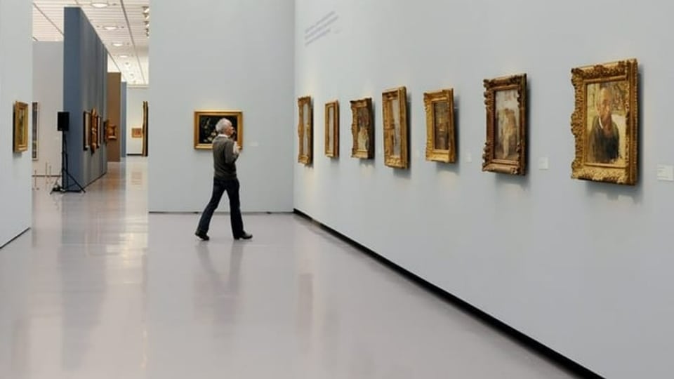 Ausstellungsaufnahme, mehrere Bilder an einer weissen Wand. Ein Mann betrachtet die Bilder.