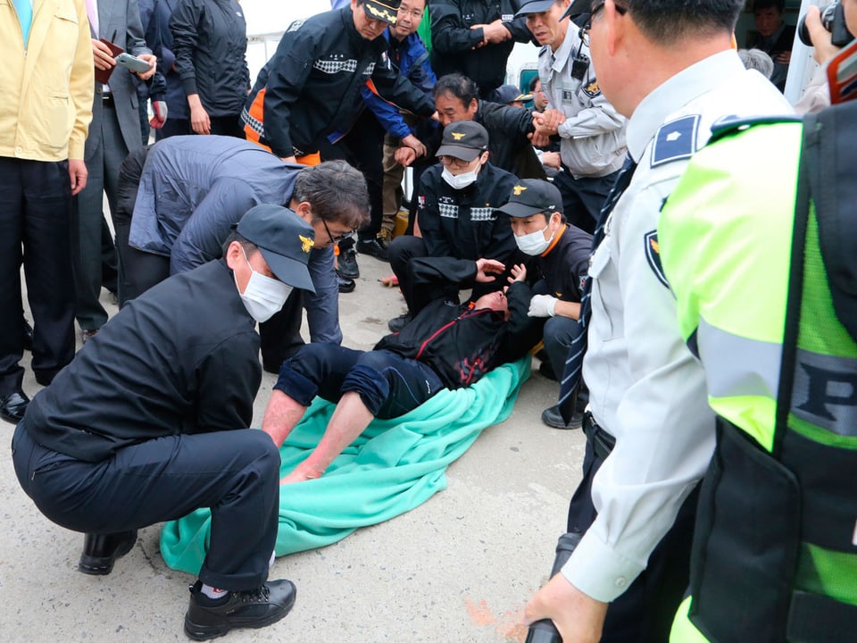 Ein Passagier wird von Rettungskräften in ein Tuch gelegt.