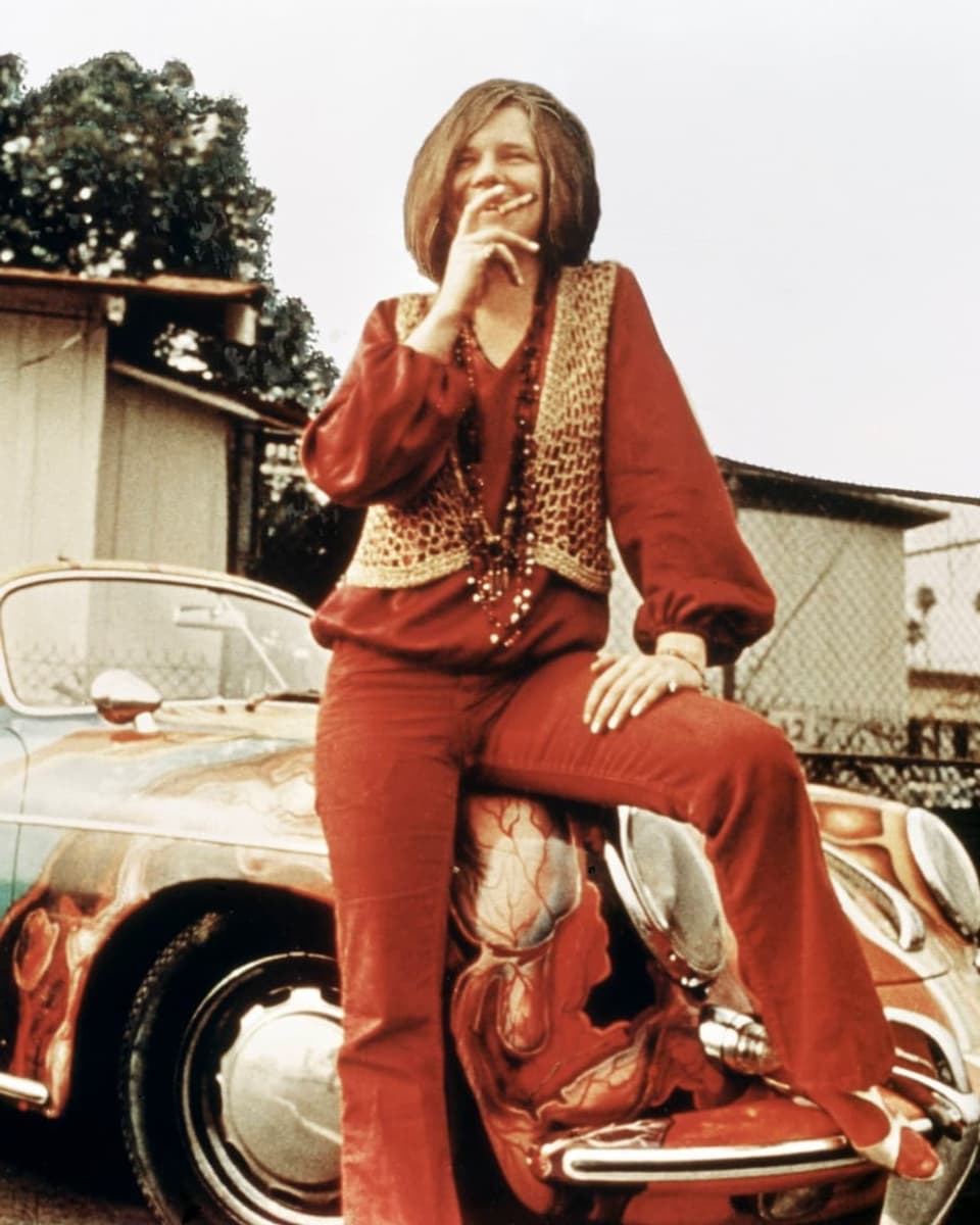 Janis Joplin posiert vor einem bunten Porsche.