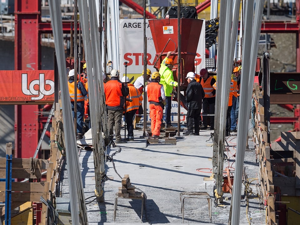 Bauarbeiter betonieren auf dem Brückenbogen.