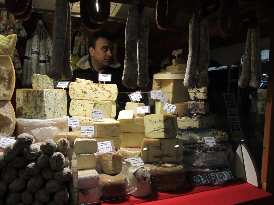 Ein Mann steht in einem Stand hinter einer grossen Käseauslage.