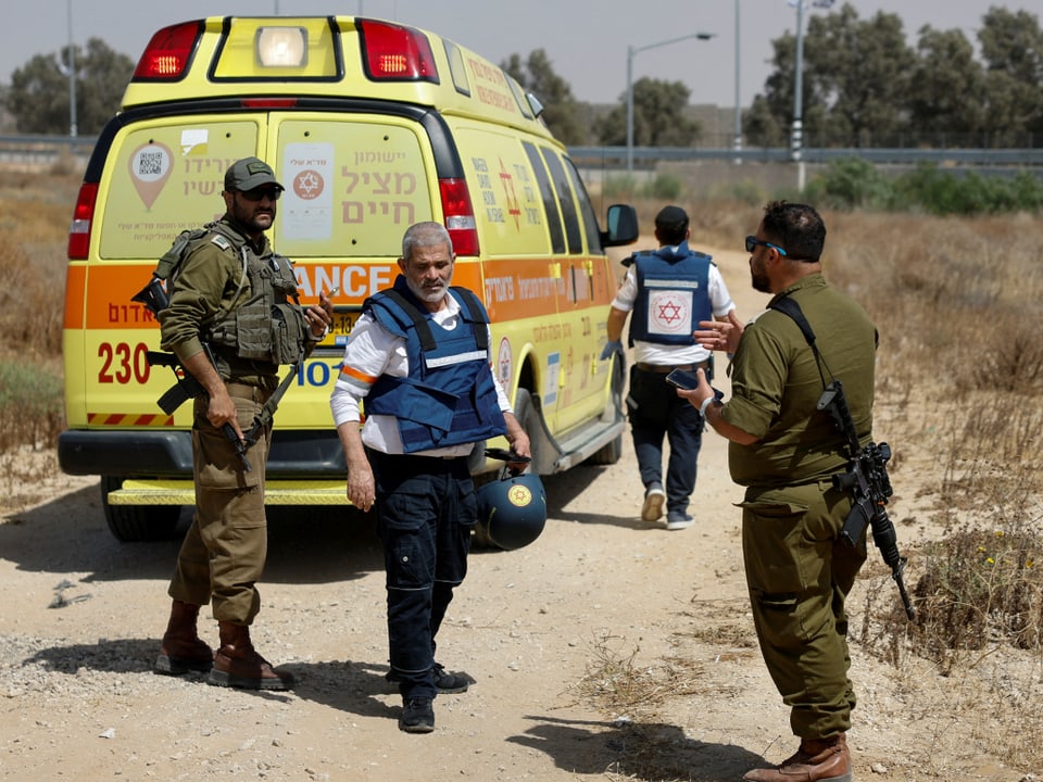 Sanitäter und bewaffnete Soldaten vor einem Krankenwagen in Israel nach Angriff auf Kerem Schalom.
