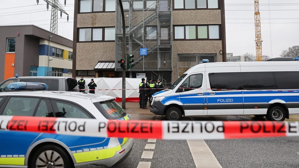 Polizei-Absperrband, Polizei-Fahrzeuge und Einsatzkräfte stehen vor einem Gebäude mit der Aufschrift «JW.ORG».