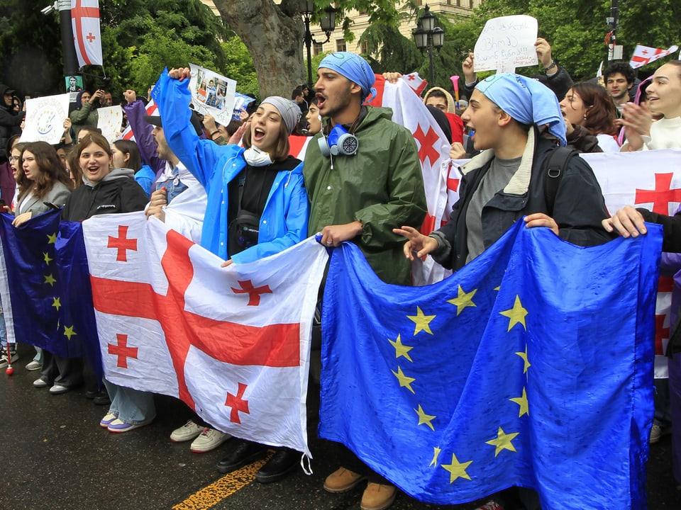 Menschen bei einer Demonstration mit georgischen und europäischen Flaggen.