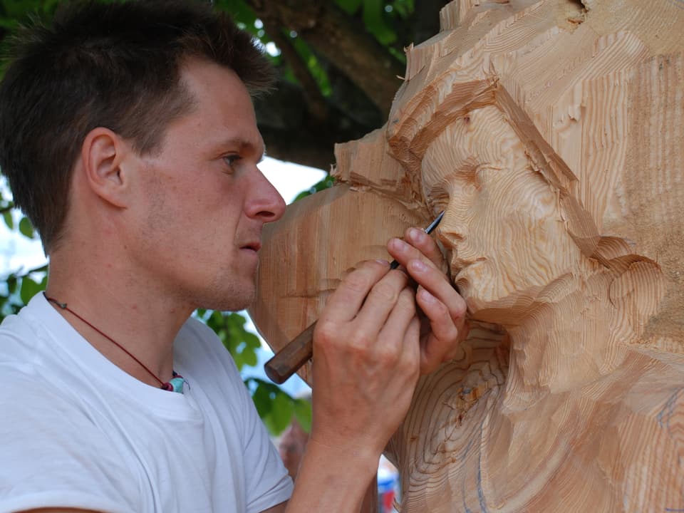 Gianluigi Zeni aus Italien schnitzt an einem Frauengesicht aus Holz.