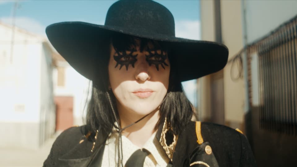 Eine Frau mit schwarzem Hut und viel schwarzer Schminke um ihre Augen