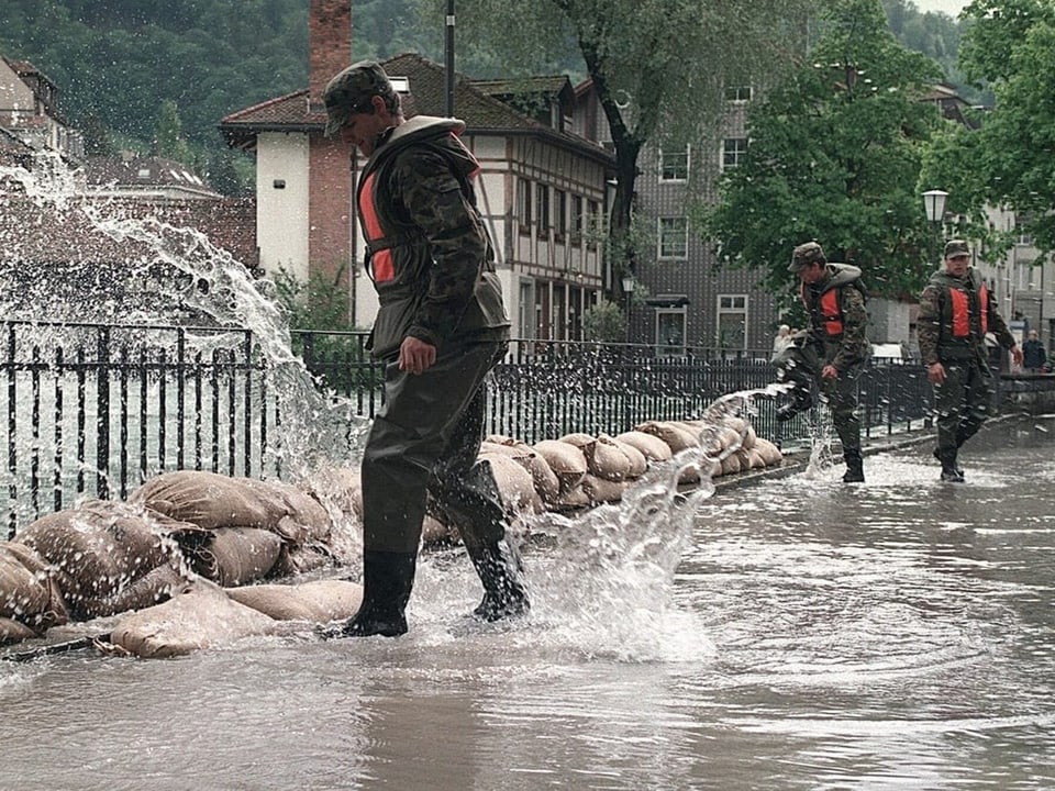 Soldaten inspizieren Sandsackbarrieren bei Überschwemmungen in einer Stadtstrasse.