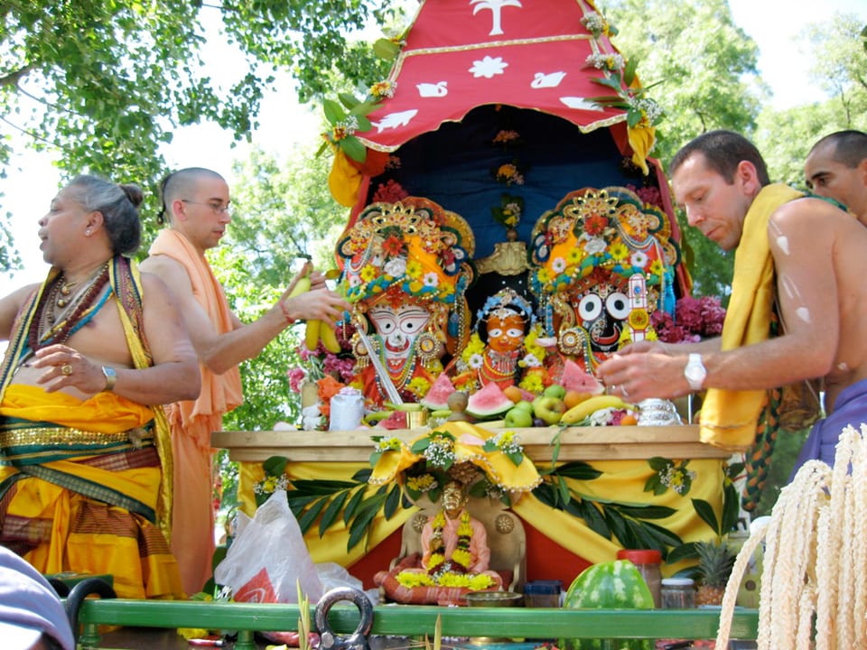 Menschen legen Früchte bei einem bunten indischen Altar nieder. 