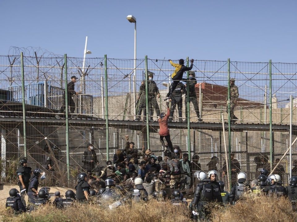 Migranten versuchen, über den Grenzzaun bei Melilla zu klettern.