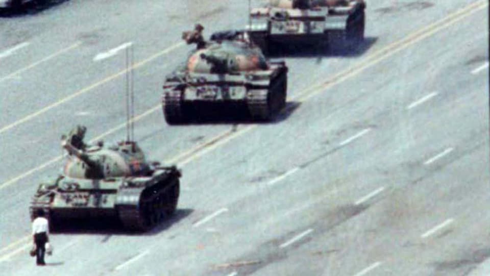 Eine Person steht vor einer Panzerkolonne.