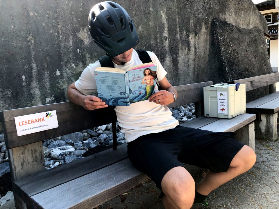 Reto Scherrer sitzt auf einer Bank und liest.