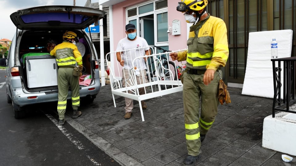 Einsatzkräfte helfen einem Bewohner von Todoque beim Tragen von Möbeln.