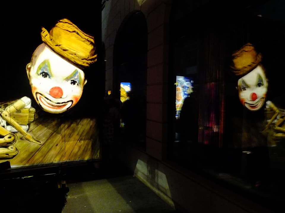 Laterne mit Clown, die sich in Schaufenster spiegelt.