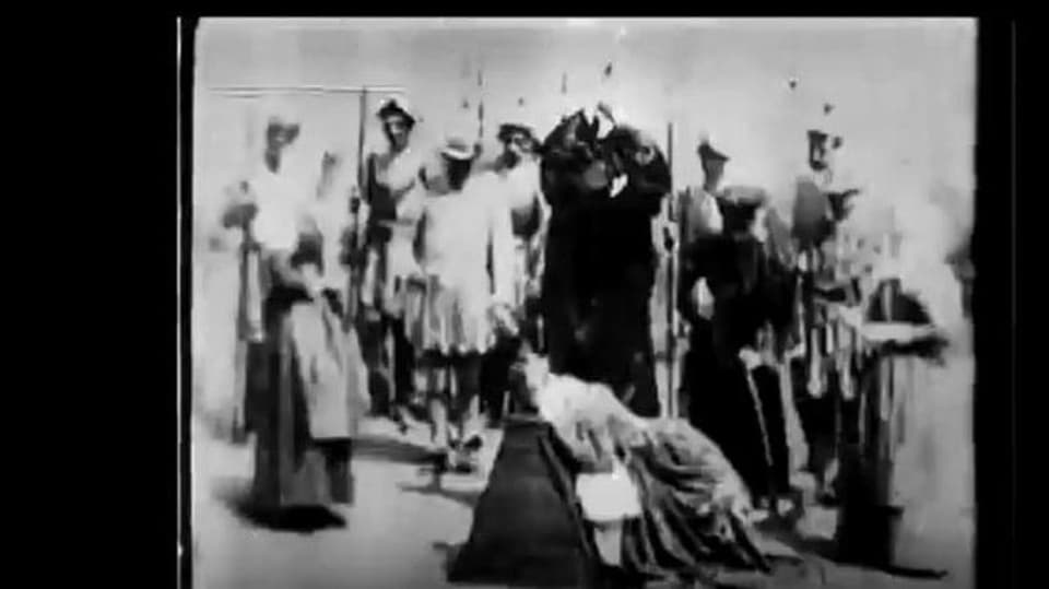 Szene aus einem alten Film: Ein Henker hebt ein Beil, vor ihm kniet eine Frau. Darum herum eine Menschenschar.