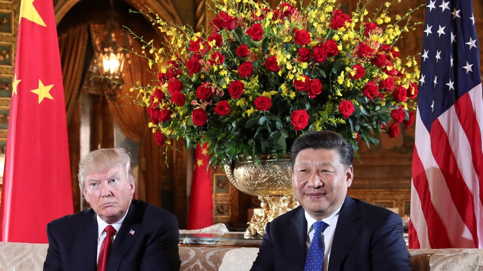 Trump und Xi vor einem grossen Blumenstrauss und den USA- und Chinaflaggen.