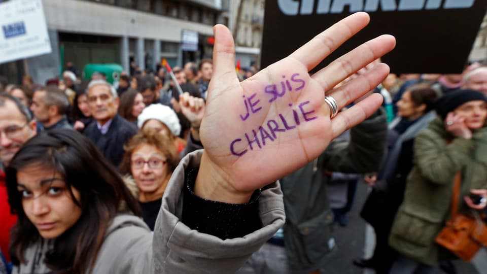 Eine Teilnehmerin des Gedenkmarsches in Paris hebt ihre Hand in die Kamera, auf der «Je suis Charlie» steht