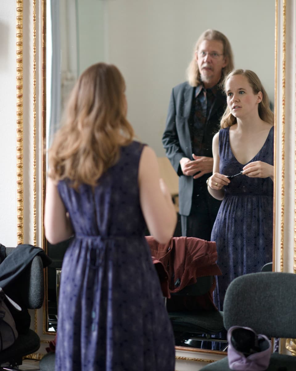 Eine Frau in einem eleganten Kleid und ein Herr vor einem grossen Spiegel.