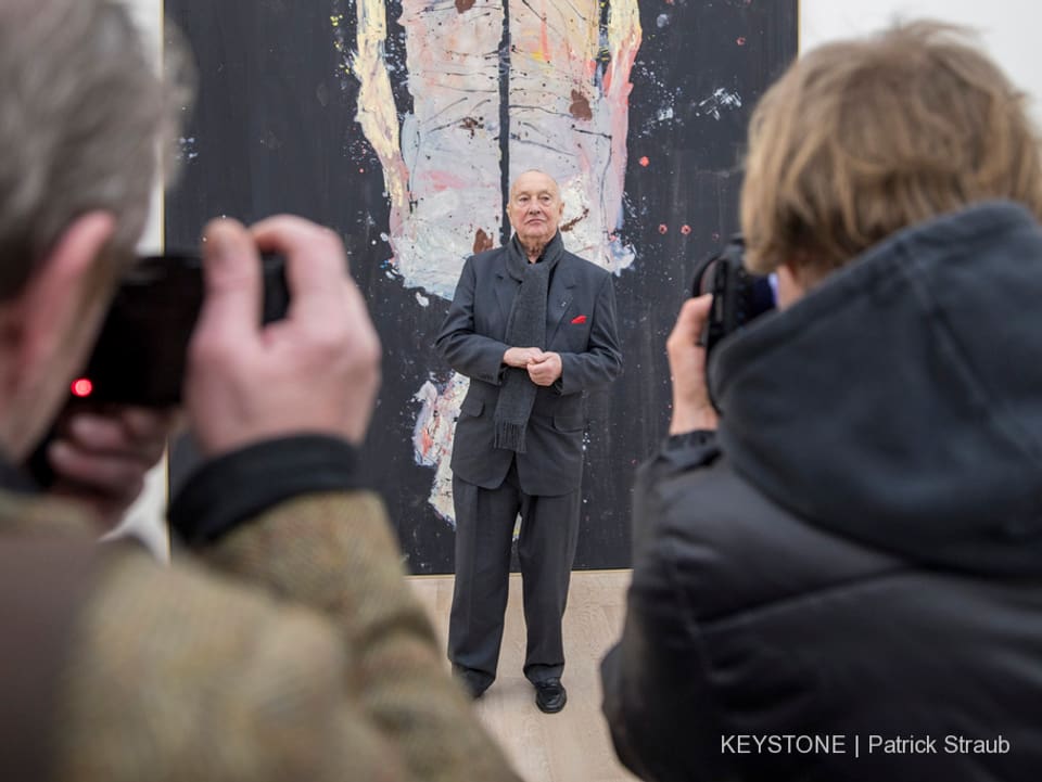 Georg Baselitz posiert vor einem seiner Bilder für Fotografen.