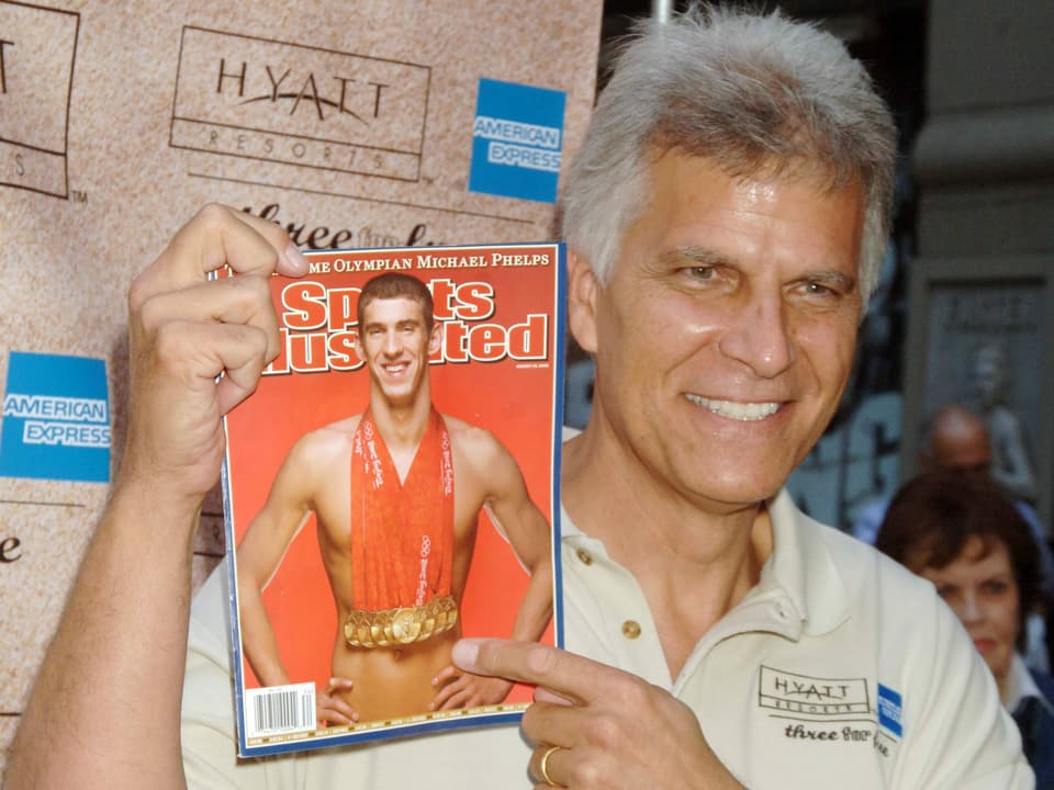 Mark Spitz mit einer Zeitschrift von Michael Phelps.