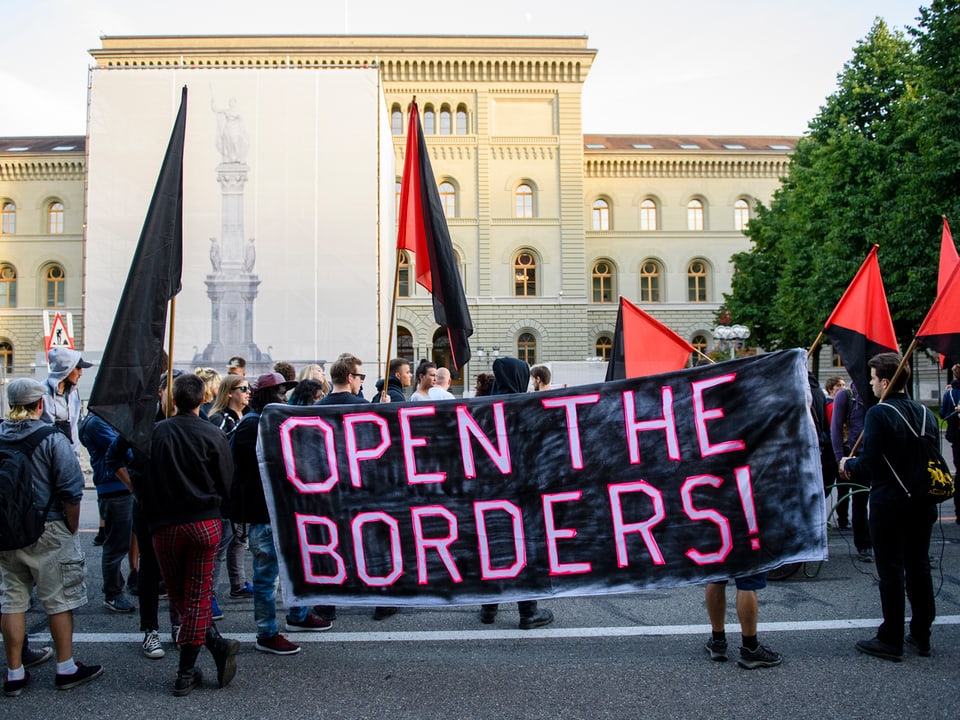 Linke Demonstranten mit Fahnen und «Öffnet die Grenzen»-Transparenten