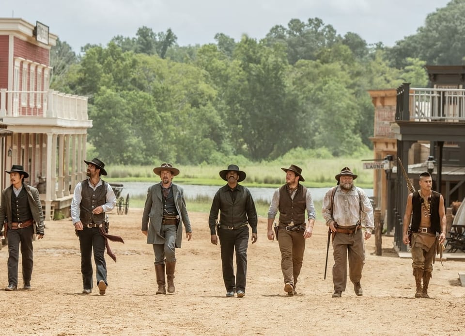 Sieben Cowboys laufen in Veste und Hut durch ein Western-Dorf in den USA