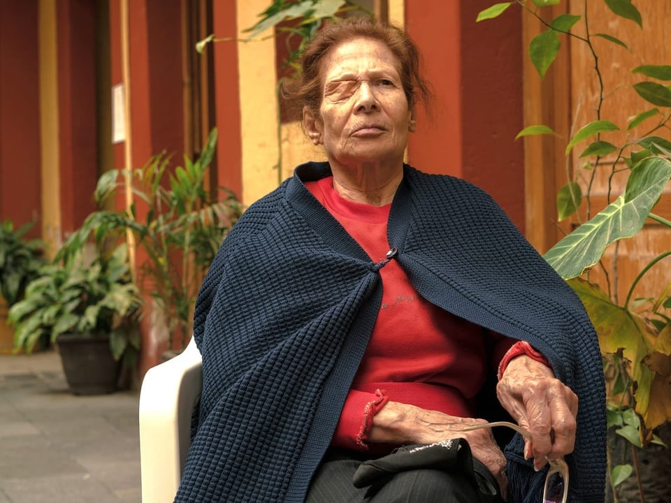 Portrait einer Bewohnerin des «Casa Xochiquetzal» sitzt in einem Stuhl und trägt eine Augenbinde.