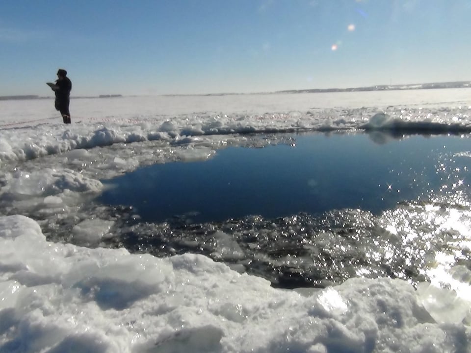Grosses Loch in der Eisdecke auf einem See.