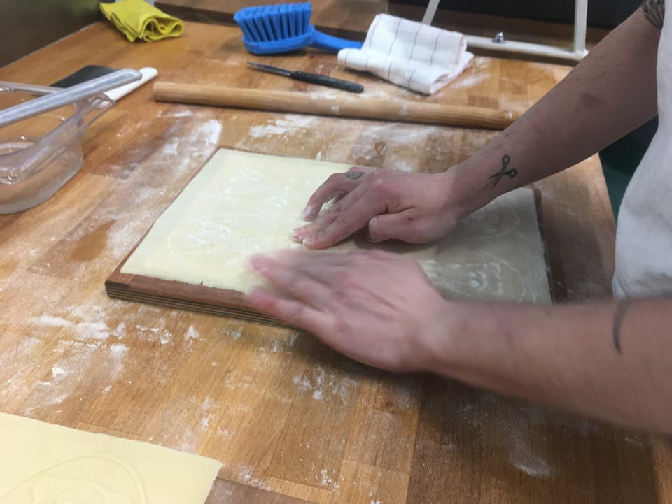 Ein Bäcker drückt sachte Teig in ein Model.