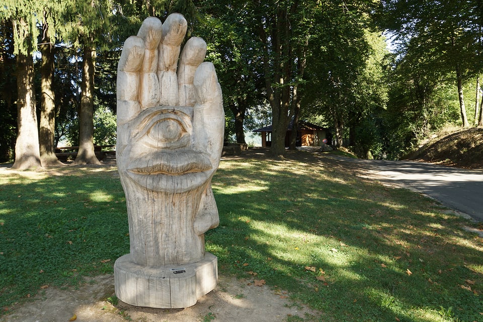 Eine grosse Hand aus Holz mit eingeschnitztem Auge, Mund und Ohr.