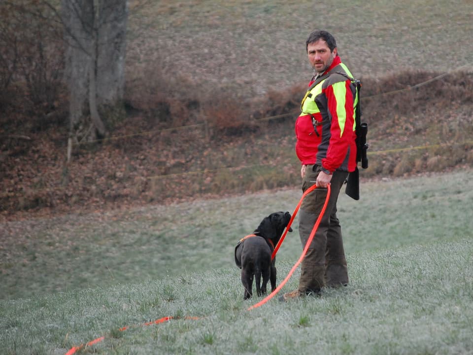 Wildhüter mit Hund auf offenem Feld.