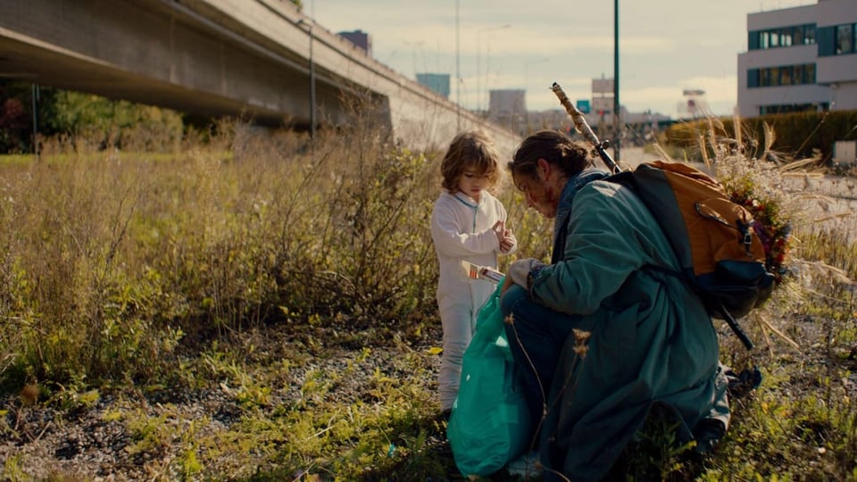 Eine Frau und Kind auf einer Wiese unterhalb einer Autobahn