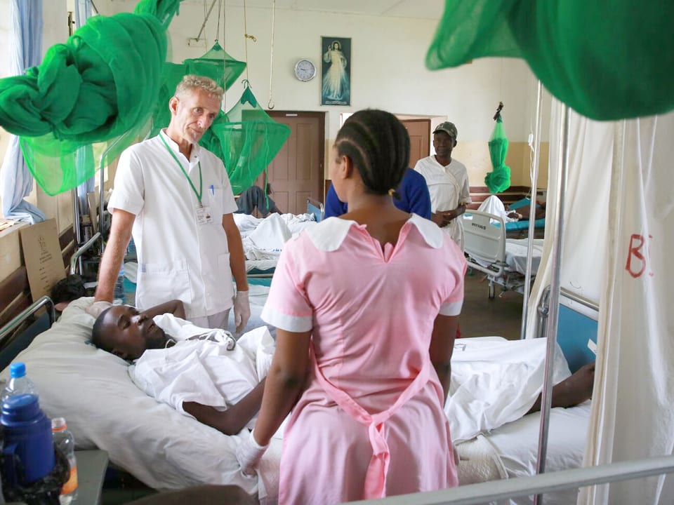 Eine Pflegerin und ein Arzt stehen in einem Spital in Tansania am Bett eines Patienten.