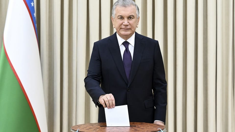 Mann mit grauen Haaren und dunklem Anzug wirft einen Umschlag in eine Wahlurne