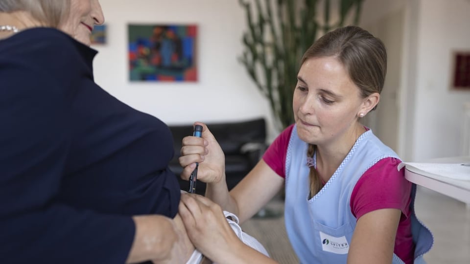 Eine Mitarbeiterin der Spitex gibt einer Klientin eine Insulin-Spritze in den Bauch.