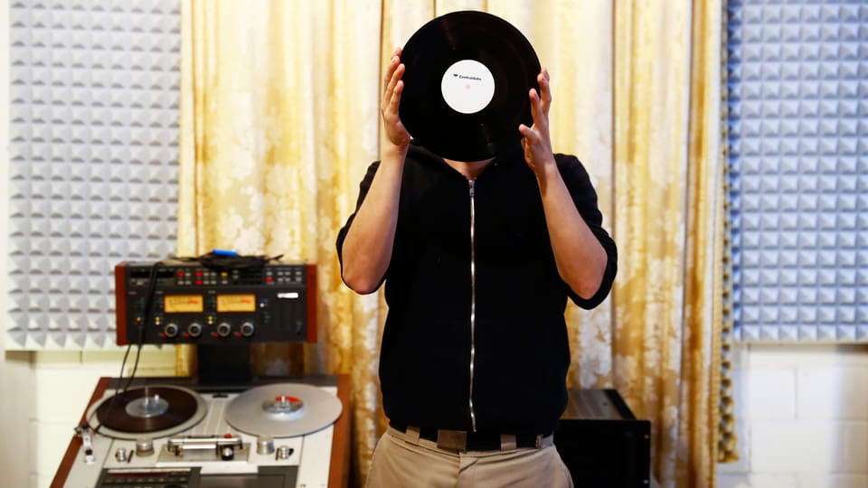 Ein Mann hält eine Vinyl Schallplatte vor sein Gesicht.