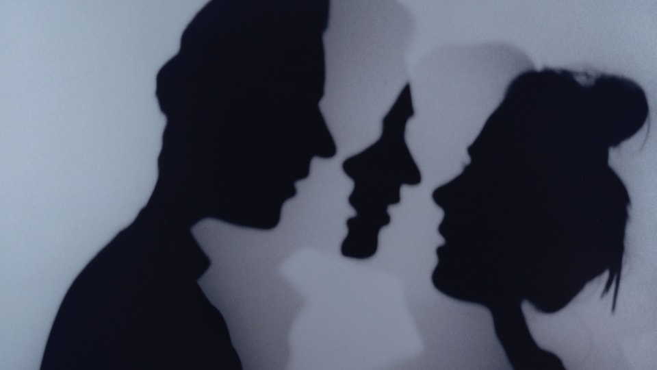 Silhouetten von einem Mann und einer Frau, die sich zu küssen gedenken. 
