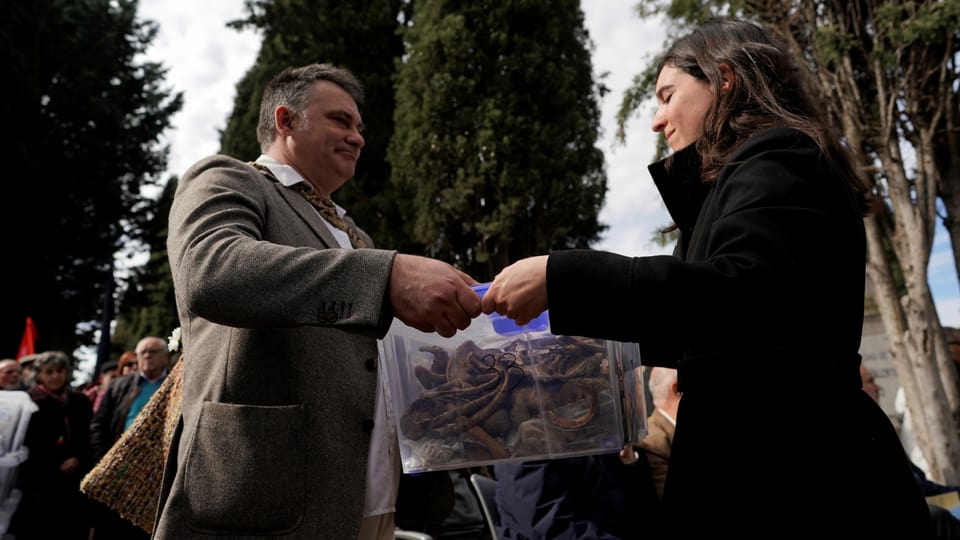 Mann übergibt einer Frau eine Plastik-Box mit menschlichen Knochen