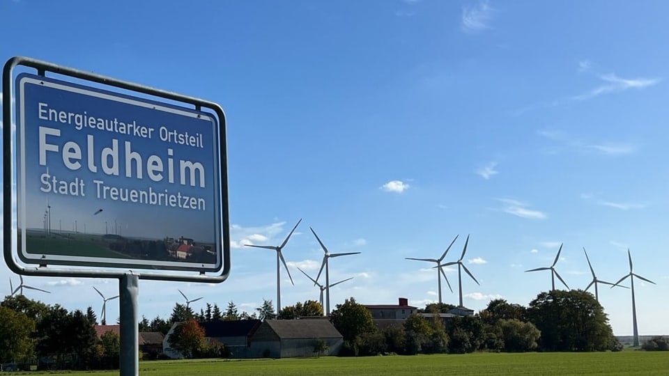 Ortseingangsschild von Feldheim, Windräder im Hintergrund