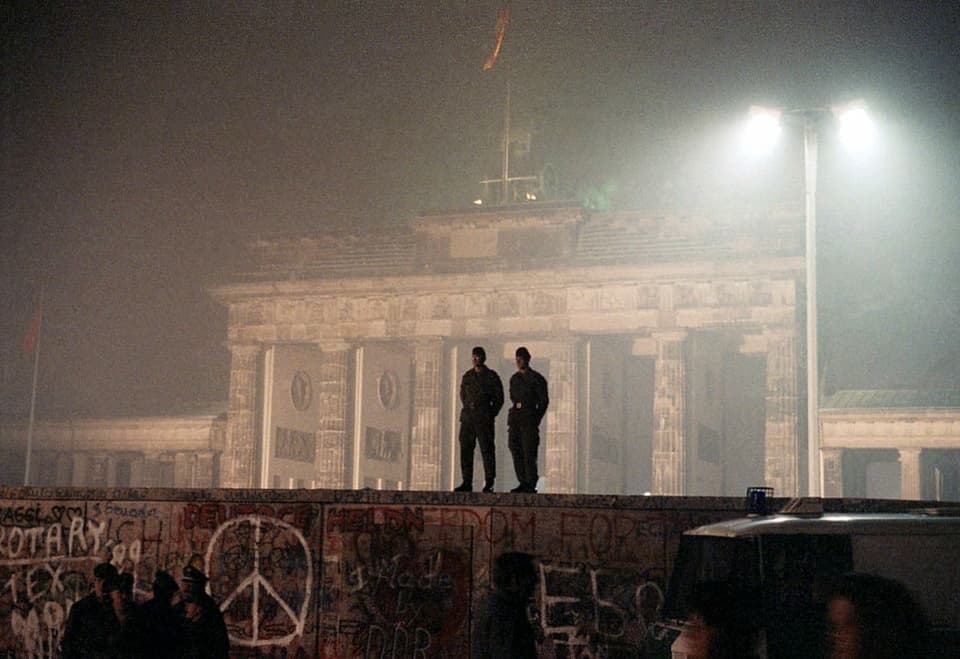 Die Silhouetten von zwei DDR-Grenzsoldaten auf der Berliner Mauer.