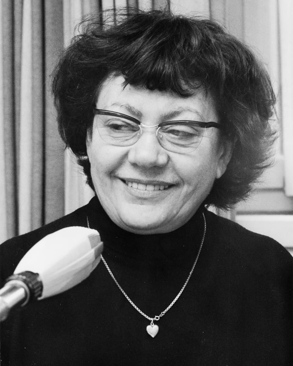 Porträtbild von Margrit Rainer mit Brille, in dunklem Pullover und mit einer Herzkette.
