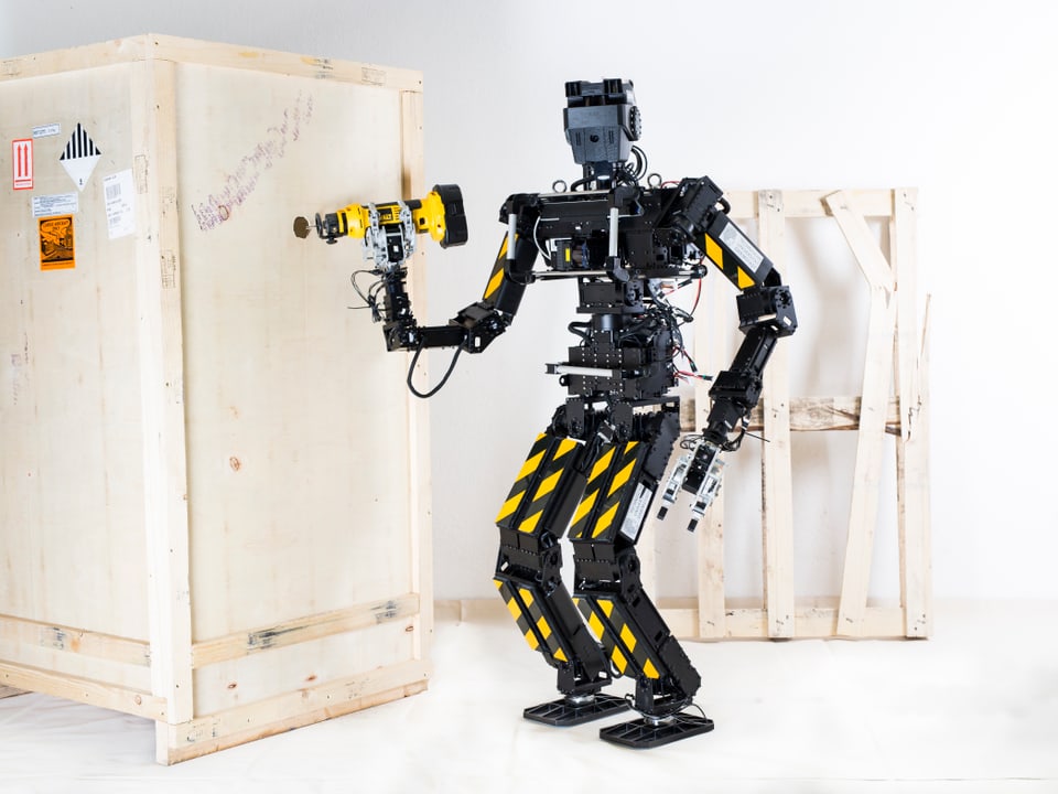 Ein Roboter bohrt mit einem Werkzeug ein Loch in eine Holzwand.